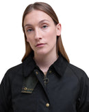Black women’s wax jacket close-up with stand collar and gold-tone snap buttons